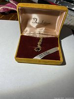 Pendant and chain inside Tradition box, 10K gold ribbon visible