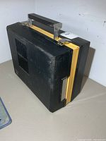 Closed black suitcase-style 8-track player showing handle and yellow trim