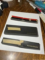 Three presentation boxes: two black PaperMate cases and one red/black sleeve