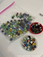 Bag and two dishes of assorted marbles in various colors and patterns