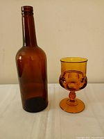 Amber glass bottle and goblet side by side