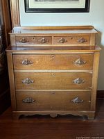 Front view of walnut dresser showing five drawers and carved pulls