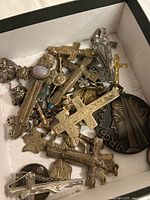 Top view of box showing assortment of crucifixes, medallions and coins