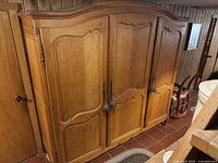 Front view showing three paneled carved doors with tasselled keys and arched cornice