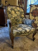 Front view of carved wood armchair with floral upholstery