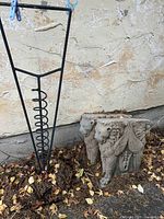 Metal plant support and two cement winged lion statues together