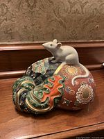 Front view of porcelain rat on ornate sack