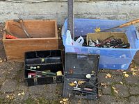 Four containers: wooden crate, blue tote, black toolbox, black hard case