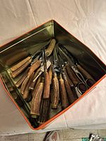 Overview of tin box filled with stag horn handled utensils