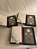 Overview of three Royal Canadian Mint proof sets open showing coins and specification cards