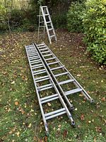 Two straight ladders laid on grass, full length view