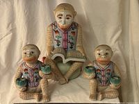 Front view of all three porcelain monkey figurines