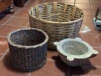 Three items grouped: two wicker baskets, one stone mortar bowl