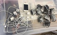 Overview of lot showing iPhone, white Apple adapters and cables, and wrapped black chargers