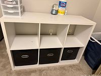 Front view of white 6-cube cabinet with three black fabric bins inserted