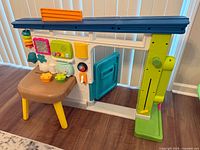Front view showing blue roof, white frame, activity table, lantern toy and turquoise door