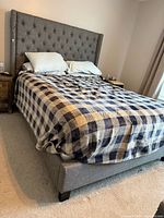 Full view of grey upholstered queen bed with headboard, mattress, bedding