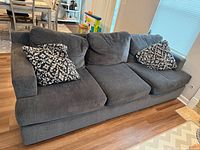 Grey three-seat sofa with two patterned pillows