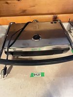 Grill closed showing stainless lid, power cord, US plug