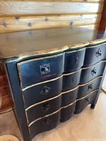 Front view showing serpentine drawers, distressed black and gold finish