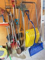 Group of garden and snow tools leaning against wall