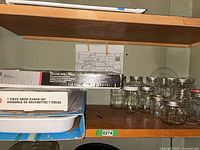 Shelf showing boxed kabob set, boxed grill rack and mason jars