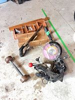 All four items on floor: sharpener, hand saw, post anchor, dumbbell