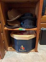 Two hats on wooden shelf with Biltmore hat box underneath