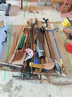 Pile of assorted long-handled yard tools on a board