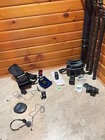 Overall view of all items including camera, lenses, bags, tripod poles, headset, binoculars and accessories laid out on floor