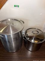 Large and medium stainless steel stock pots with lids side by side