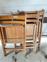 three folded solid wood chairs leaning together