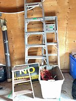 overall lot with both aluminum ladders, wooden stool, sign, tote with cords