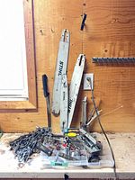 Overview of three Stihl guide bars, pile of chains and assorted tools on workbench