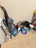 Hoover SteamVac, Tineco stick vacuum, box of hoses and tools on floor