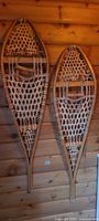 full view of both wooden snowshoes hanging on wall