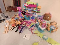 Group view of dolls, baby dolls, playset and accessories on tabletop
