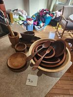 overview of assorted wooden bowls, utensils, mortar and pestle on countertop