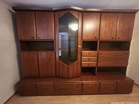 Front view of the full teak wall unit showing all cabinets, drawers, and glass display section