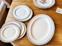 Stacks of plain rim plates and oval platter with grey-gold border