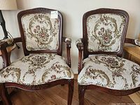 Front view of both carved wood armchairs with floral upholstery