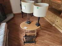 Overall lot showing two lamps on oval side table with magazine rack beneath