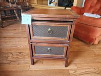 Front view of wood side table showing two drawers with brass ring pulls