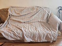 Beige quilted cover draped over sofa showing size and quilting