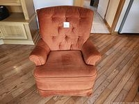 Front view showing tufted back, rolled arms, seat cushion, skirted base
