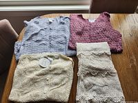 Four folded crochet and lace tops in blue-grey, mauve, ivory and white