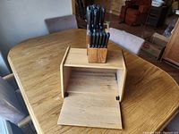 Bread box open with wood knife block and knives visible
