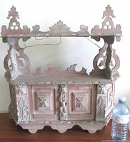 Full view of carved limed oak wall cabinet with water bottle for scale