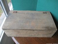 Top view of closed wooden tool box showing lid and hinges