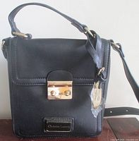 Front view of Christian Lacroix Lucie camera bag showing clasp, logo plaque, top handle and strap